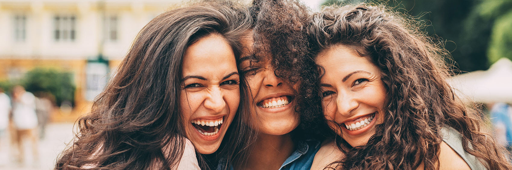 Three young women embracing and smiling at the camera