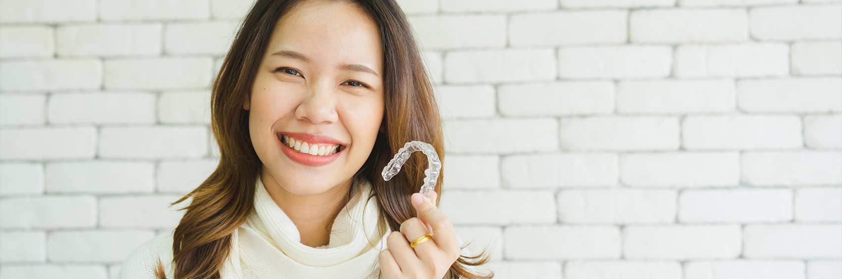 "Woman smiling and holding Invisalign"