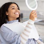 "Woman smiling at her reflection in a mirror"