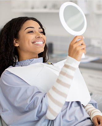 "Woman smiling at her reflection in a mirror"