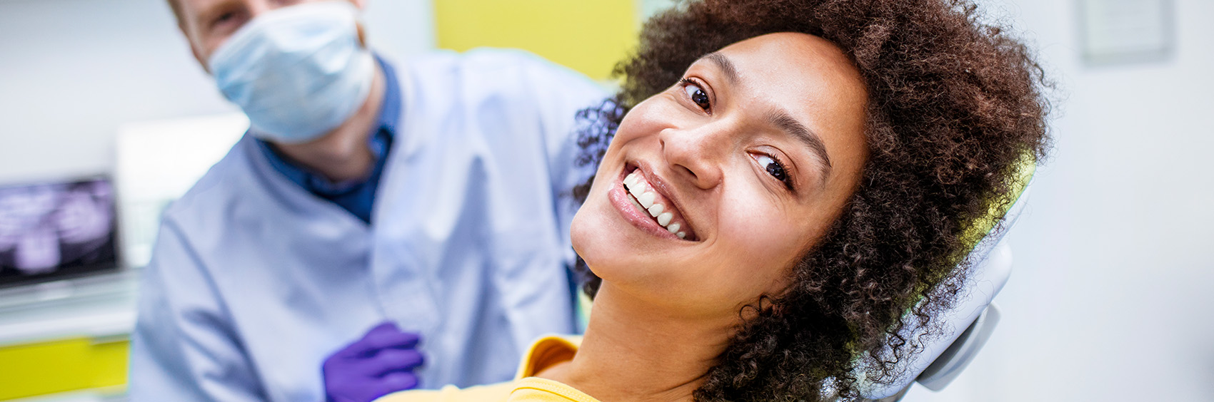 "Woman smiling while sitting at a dental office"