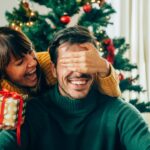 woman gifting man christmas present, gift yourself a new smile this Christmas with teeth whitening, veneers, Invisalign, dental implants, or crowns